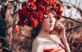 Молодая девушка азиатка с красными цветами на голове