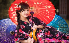 Молодая азиатка в кимоно с разноцветными зонтиками