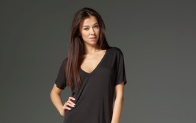 Молодая брюнетка в черном наряде фото на сером фоне