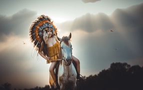 Молодая девушка в костюме индейца на коне