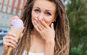 Young girl with dreadlocks on her head and with ice cream in her hands