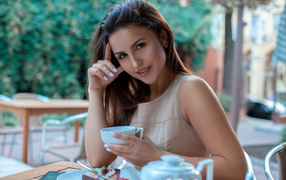 Молодая улыбающаяся девушка с чашкой кофе в кафе