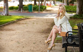 Красивая девушка фотомодель Кенна Джеймс сидит на лавке в парке