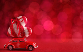 Красная игрушечная машинка везет с сердечко на розовом фоне, фон для открытки на День Святого Валентина