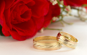 Золотые обручальные кольца с рисунком и красные розы на свадьбу