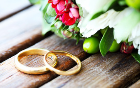 Два золотых обручальных кольца с букетом цветов