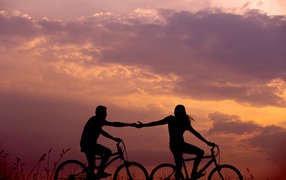 A loving couple on bicycles is riding at sunset