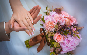 Hands of a loving couple with bridal bouquets