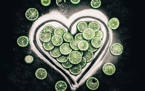 Heart made of sugar and circles of green lime on a black background