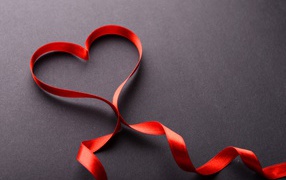 Red heart from a satin ribbon on a gray background