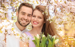 Smiling loving couple by the flowering tree