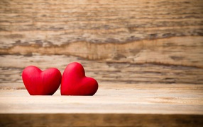 Two red hearts lie on a wooden bench
