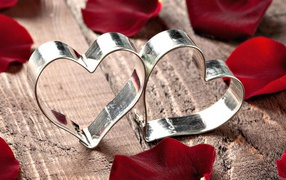 Два серебряных сердца в лепестках красной розы 