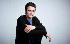 Актер Джеймс Франко в черной кофте на сером фоне