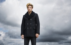 Актер Джеймс Нортон в черном пальто на фоне неба