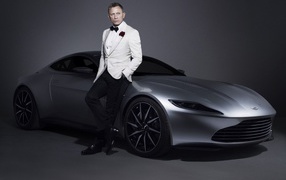Знаменитый актер Дэниел Крэйг рядом с серебристым автомобилем Aston Martin
