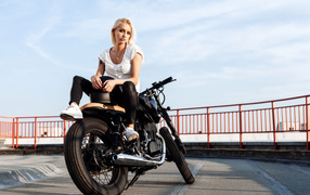 Красивая блондинка сидит на черном мотоцикле