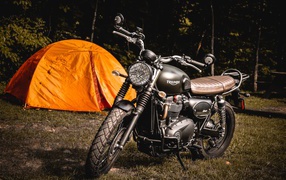 Black motorcycle Triumph on the background of an orange tent