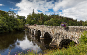 Мост через реку у леса на фоне красивого голубого неба с белыми облаками. Ирландия