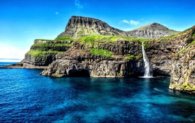 Маленький водопад стекает со скалы в океан, Гавайские острова