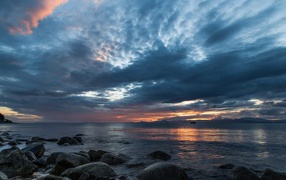 Валуны в воде на берегу на фоне пасмурного неба 
