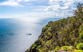 Утес на берегу океана на фоне красивого голубого неба