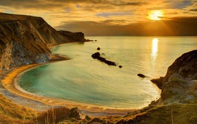 Скалы на берегу океана в лучах солнца на закате