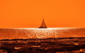 Парусная лодка на горизонте в океане на закате солнца