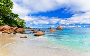 Большие камни на белом песке у голубой воды океана