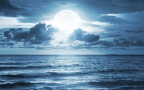 Большая луна в облаках над океаном