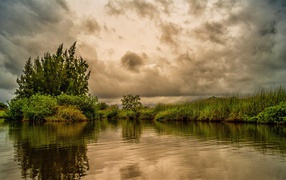 Облака над озером с покрыми зеленой травой берегами