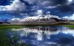 Белые облака отражаются в воде  горного озера 