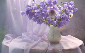 Букет фиолетовых колокольчиком в белой вазе на столе