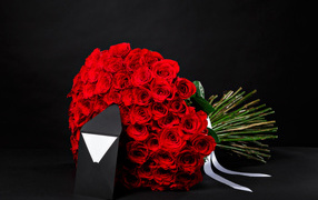 A large bouquet of red roses with an envelope on a black background