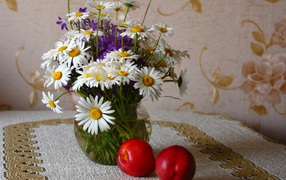 Букет белых полевых ромашек в вазе на столе с розовыми персиками