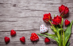 Красные красивые тюльпаны с сердечками на деревянной поверхности