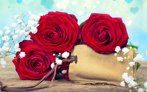 Три больших красных розы с тканевым мешочком