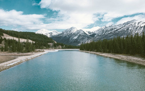 Чистая голубая вода в реке на фоне заснеженных гор 