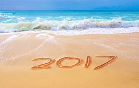 Надпись 2017 на песке у бушующего моря