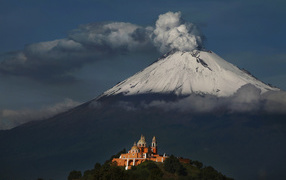 The smoking peak of the volcano Popocatepetl in the sun