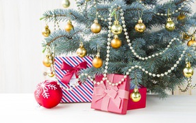 Подарки под зеленой наряженной елкой с золотыми шарами