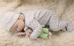 A baby baby sleeps with a favorite soft toy