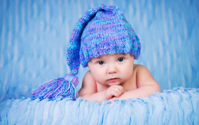 Грудной ребенок в красивой вязаной синей шапке