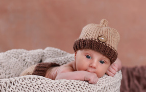 A baby child in a knitted brown hat