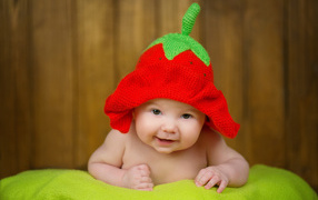 A baby in a funny strawberry head hat