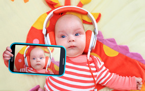 A baby in orange headphones makes selfie