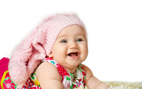 Милая маленькая улыбающаяся девочка в большой розовой шапке