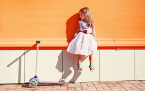 A girl in a beautiful dress with a scooter