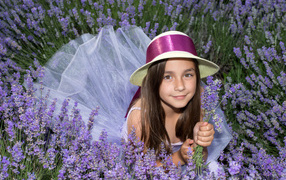 Девочка в шляпе лежит в фиолетовых цветах лаванды