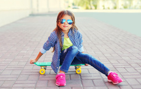 A girl in sunglasses is sitting on a skateboard